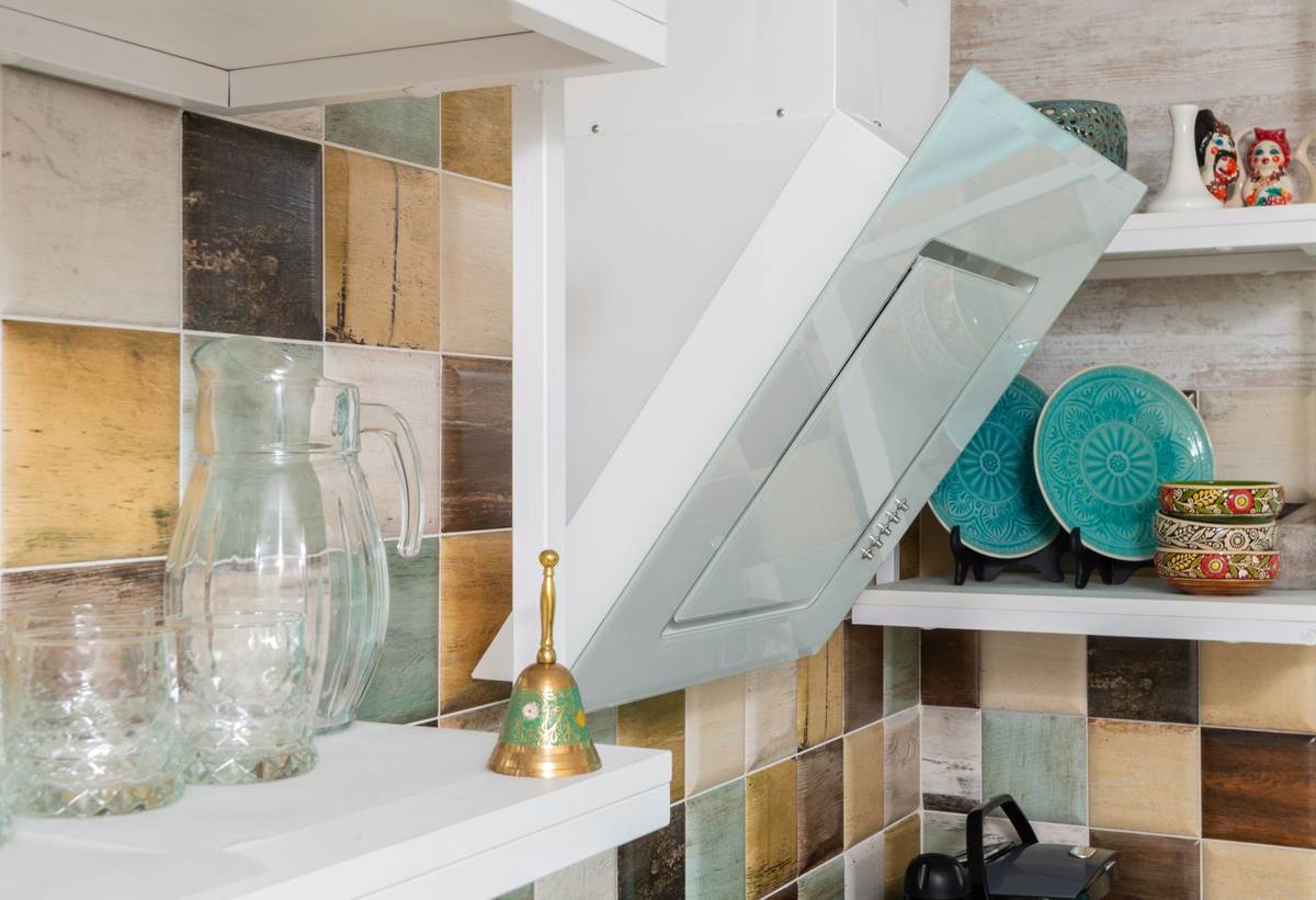 Cuisine équipée avec étagères murales contenant vaisselle, verres et accessoires de décoration