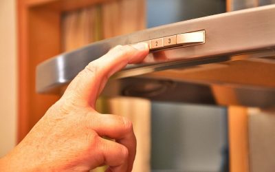 Main d'une personne actionnant une hotte aspirante en inox dans une cuisine