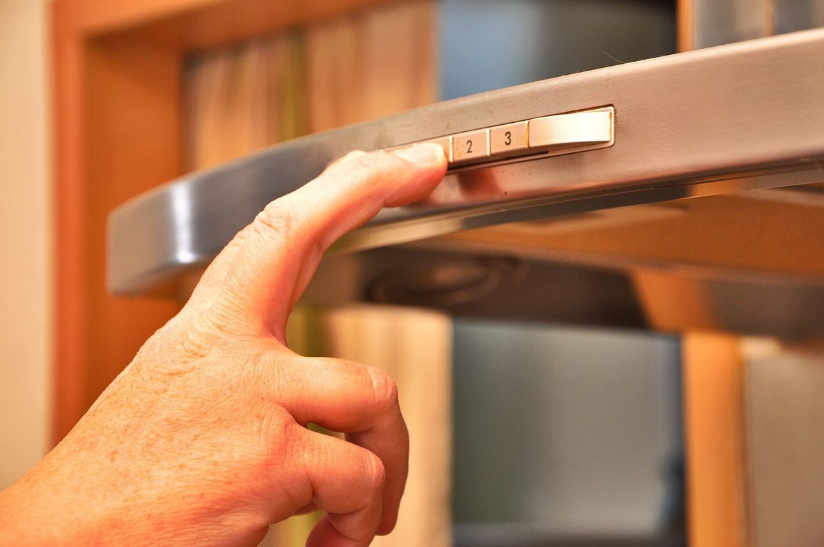 Main d'une personne actionnant une hotte aspirante en inox dans une cuisine