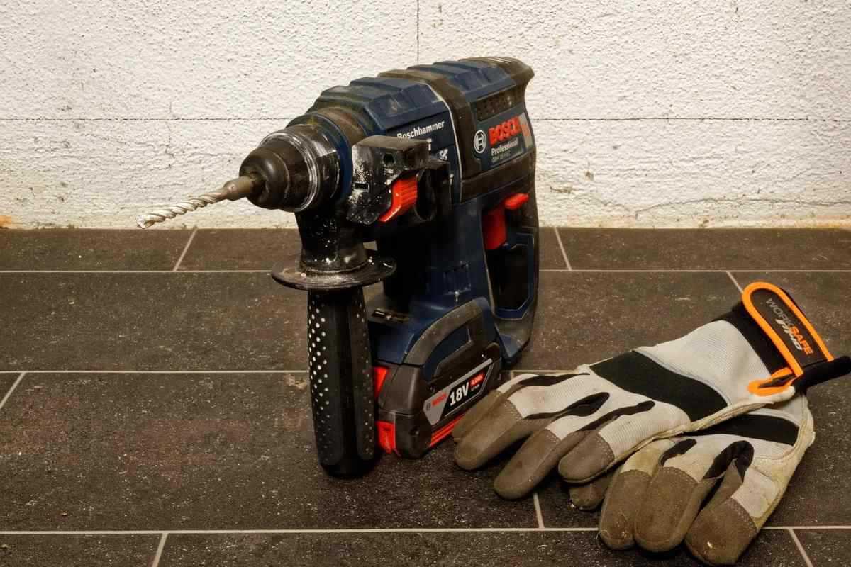 Perceuse et gants de travail sur un sol en carrelage Perceuse et gants de travail sur un sol en carrelage