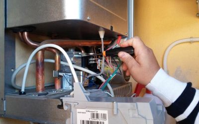 Main à l'intérieur d'un appareil chauffant manipulant des câbles électriques