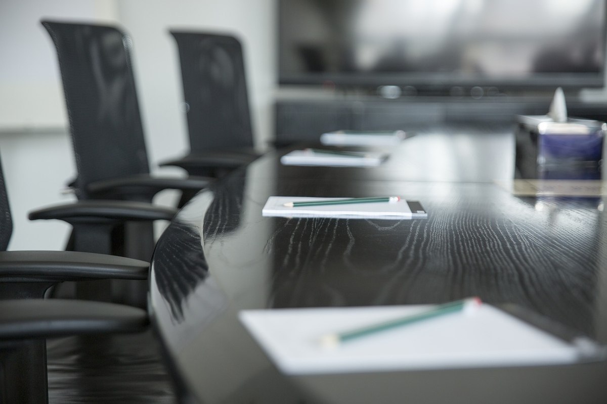 Une table de conférence avec chaises, cahiers et stylos