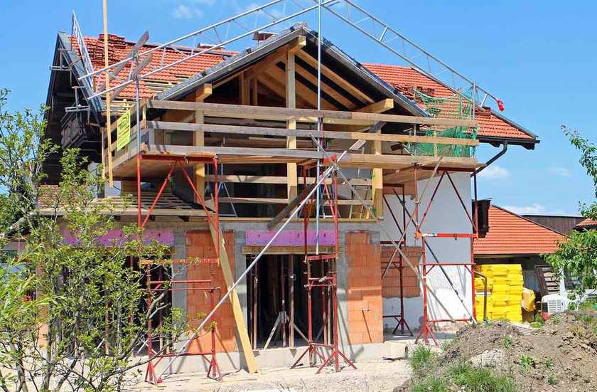 Construction d'une maison avec échafaudage, toit en tuiles, sous ciel bleu Construction d'une maison avec échafaudage, toit en tuiles, sous ciel bleu