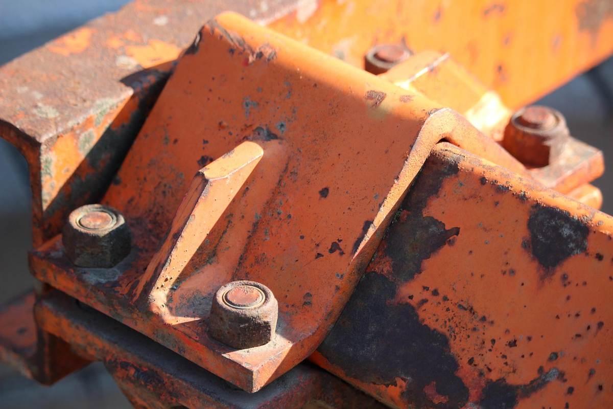 Pièces métalliques orange rouillées fixées par des boulons sur une structure extérieure Pièces métalliques orange rouillées fixées par des boulons sur une structure extérieure